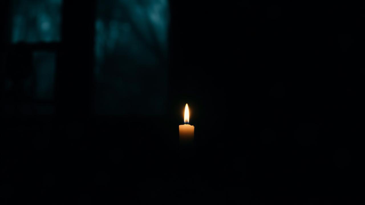 A single candle glowing in a dark quiet room — staying sober during the holidays